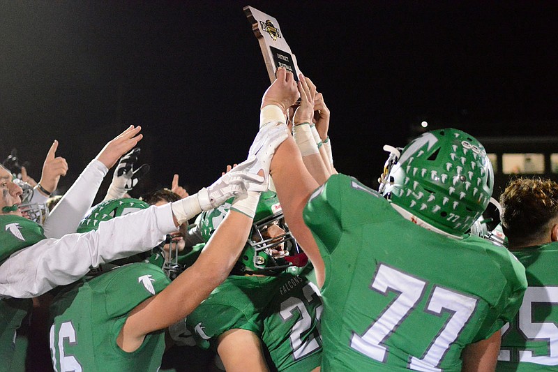 The Blair Oaks Falcons hold up the Class 3 District 5 championship plaque after defeating Buffalo 35-7 Friday night at the Falcon Athletic Complex.