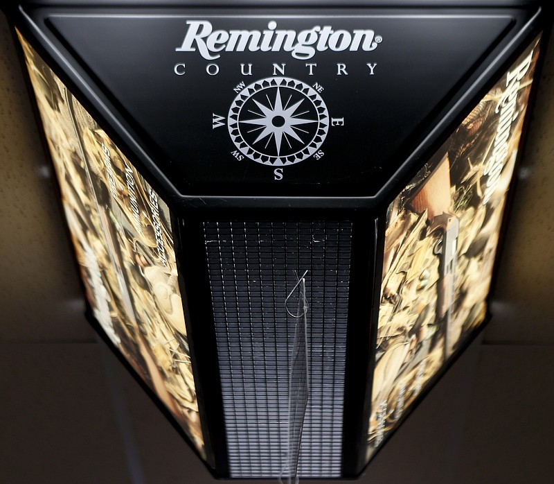 FILE - In this March 1, 2018 file photo, a light advertising Remington products hangs from the ceiling at Duke's Sport Shop in New Castle, Pa. For years, the gun industry has been immune from most lawsuits, but a recent ruling allowing families of victims in the Newton school shooting to challenge the way an AR-15 used by the shooter was marketed is upending that longstanding roadblock. The U.S. Supreme Court recently rejected efforts by gunmaker Remington to quash the lawsuit, allowing it to continue to be heard in Connecticut courts.(AP Photo/Keith Srakocic, File)
