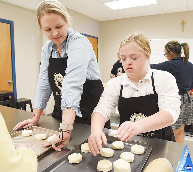 Elizabeth Twyman, left, shows Grace Theroff on Wednesday how to place the biscuits with enough space between them because they expand when they are baked. Twyman is accommodations coordinator at Helias Catholic High School where until this year, students had to go to Jefferson City High School for the life skills class. Transportation issues caused Helias to create its own program for these students. Volunteers and generous donors stepped up to help and provide the necessary kitchen appliances, tools and other items needed. 