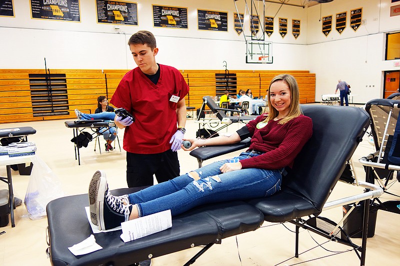 Bri Corey, right, a junior at Fulton High School, donates blood Friday with American Red Cross volunteer Jimmy Wehmeier's help. At least 60 students, teachers and community members gave blood, senior Kelly Gillespie said. The FHS Key Club organized the event.