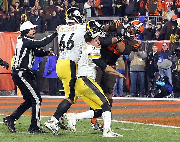 Browns defensive end Myles Garrett (95) hits Steelers quarterback Mason Rudolph with a helmet during the second half of Thursday night's game in Cleveland.