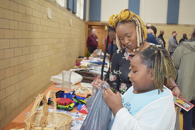 Dominique Moses and daughter Journey, 8, check out the giveaways at Sunday's World Hunger Day dinner at St. Peter Catholic Church's Selinger Center.
