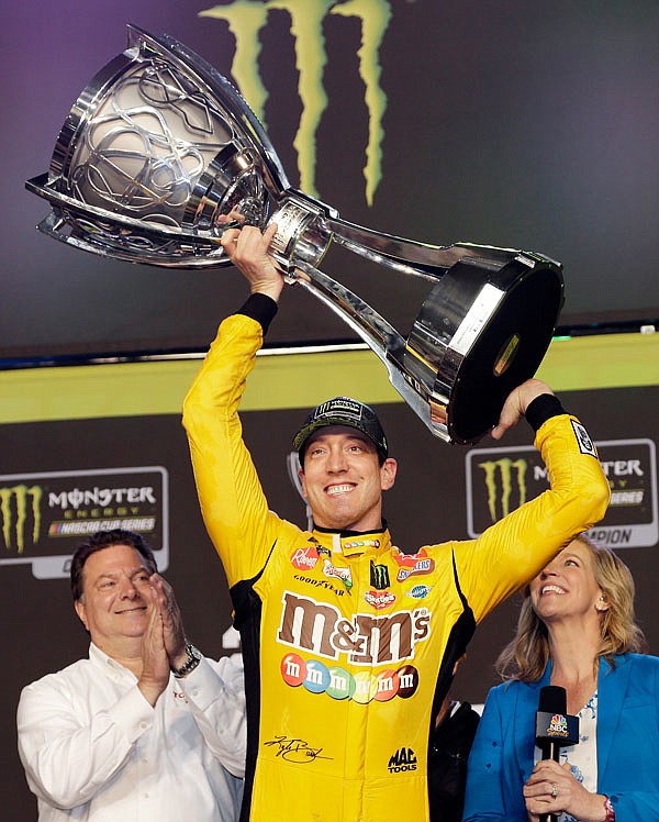 Kyle Busch holds up his trophy in victory lane after winning the 2019 NASCAR Cup Series season championship Sunday at Homestead-Miami Speedway in Homestead, Fla.