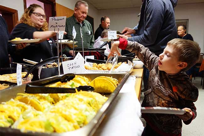 Having declared himself old enough to fix his own plate, Bentley Werdehausen of Tebbetts loads up on fried paddlefish at Sunday night's wild game dinner. The potluck meal is an annual tradition.                     