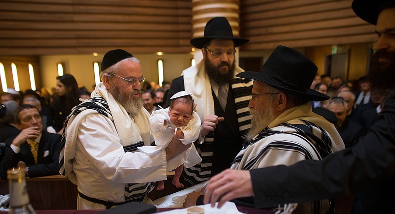  In this Sunday, March 3, 2013 file photo Mohel Manachem Fleischmann, left, holds baby Mendl Teichtal after the circumcision ceremony at the Chabad Lubawitsch Orthodox Jewish synagogue in Berlin, Germany. A new survey says about one in four Europeans hold anti-Semitic beliefs, with such attitudes on the rise in eastern countries and mostly steady in the west. (AP Photo/Markus Schreiber, file)
