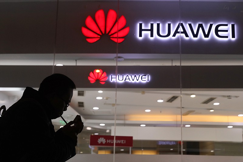 FILE - In this Dec. 6, 2018, file photo, a man lights a cigarette outside a Huawei retail shop in Beijing.  The Federal Communications Commission on Friday, Nov. 22, 2019 voted, 5-0, to bar U.S. telecommunications providers from using government subsidies to pay for networking equipment from companies that are a threat to national security. The agency says China’s Huawei and ZTE pose such a threat. (AP Photo/Ng Han Guan, File)