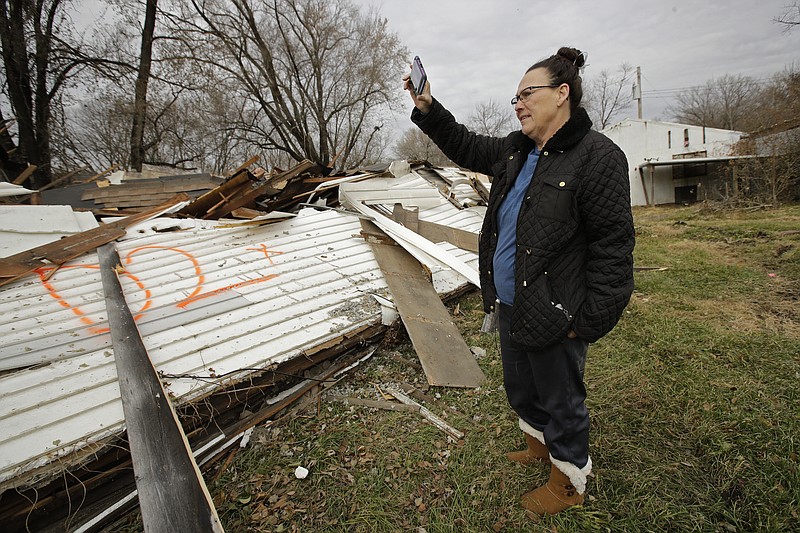 In this photo taken Monday, Nov. 18, 2019, Tammy Kilgore looks over the remains of her home after it was demolished as part of a voluntary buyout in food-prone Mosby, Mo. Kilgore accepted a $45,000 payment to leave her home of 38 years and has moved to a nearby community. (AP Photo/Charlie Riedel)