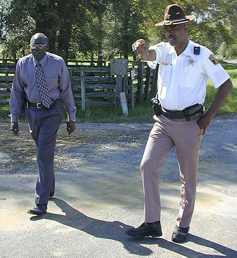 In this March 21, 2000 photo, Lowndes County Sheriff Willie Vaughner, left, and chief deputy John Williams stand at the intersection where Williams apprehended Jamil Abdullah Al-Amin on Monday evening in White Hall, Ala. Williams was fatally shot in the line of duty Saturday evening, Nov. 23, 2019, in a county near the state capital city, Alabama Gov. Kay Ivey said. Ivey tweeted that Lowndes County Sheriff Williams was “a pillar of the community.”  (Al Benn/Montgomery Advertiser via AP)