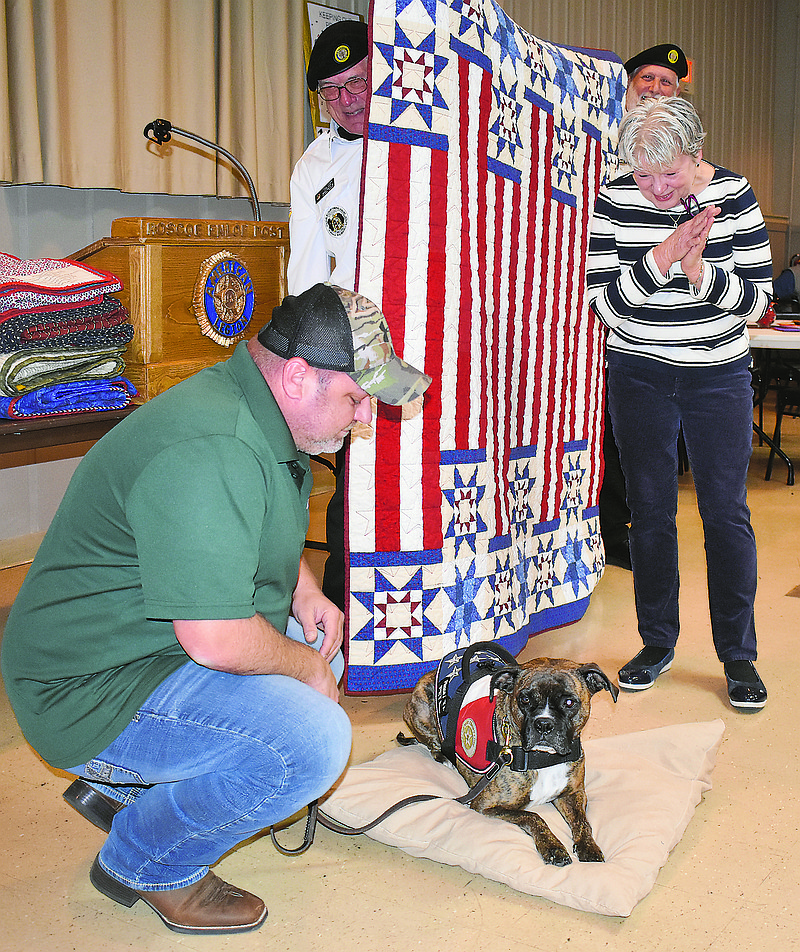 Jason Howe watches his service dog, Sobee, get acquainted with her new pillow during Sunday's Quilt of Valor ceremony at American Legion Post 5. The Quilts of Valor organization presented patriotic quilts to nine area veterans, including Howe. The group also made the pillow for Sobee. 