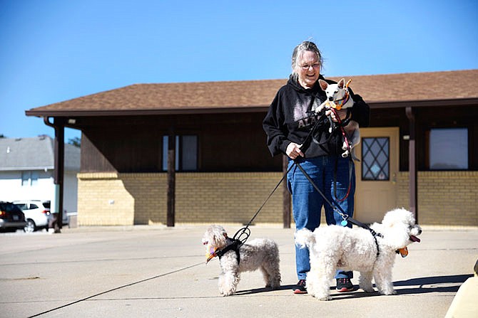 FILE: Donna Ponder holds her chihuahua, Scooter, in 2018 while walking her other two poodles, Gracie and Casper, at Westside Veterinary Clinic in Jefferson City. Ponder obtained all three of her dogs from animal shelters.