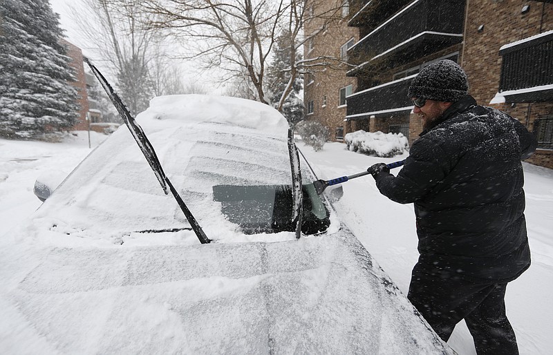 Szymon Lobocki, a rocket engineer from Denver, clears off his Subaru to drive to work in a south suburb as a storm packing snow and high winds sweeps in over the region Tuesday, Nov. 26, 2019, in Denver. Stores, schools and government offices were closed or curtailed their hours while on another front, Thanksgiving Day travelers were forced to wrestle with snow-packed roads and flight delays or cancellations throughout the intermountain West. (AP Photo/David Zalubowski)