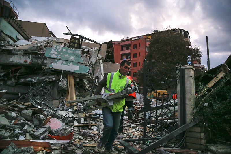 A worker removes debris from a damaged building in Durres, western Albania, Wednesday, Nov. 27, 2019. The death toll from a powerful earthquake in Albania has risen to 25 overnight as local and international rescue crews continue to search collapsed buildings for survivors. (AP Photo/Visar Kryeziu)