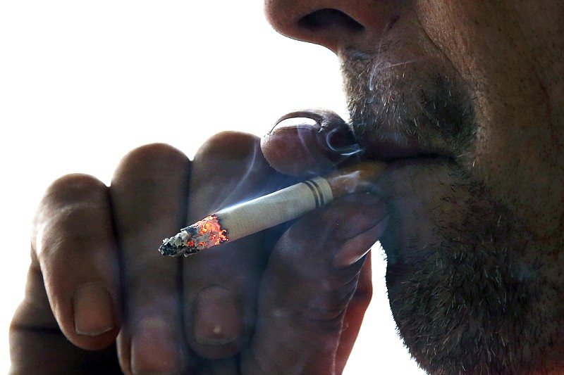 FILE - In this Nov. 6, 2014, file photo, a man smokes a cigarette on Main Street in Westminster, Mass. Massachusetts Gov. Charlie Baker is expected to sign a law on Wednesday, Nov. 27, 2019, banning sales of flavored tobacco and vaping products, including menthol cigarettes. (AP Photo/Elise Amendola), File