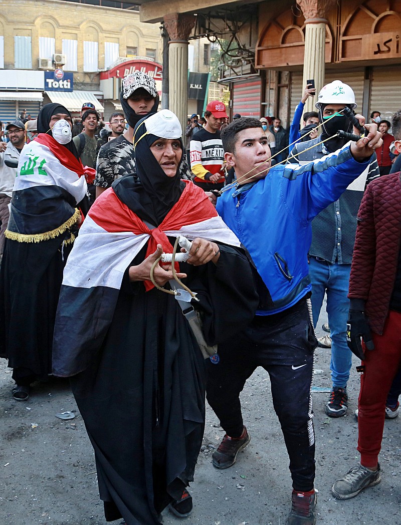 An anti-government protester uses a slingshot to fire stones at riot police during clashes in Baghdad, Iraq, Thursday, Nov. 28, 2019. Scores of protesters have been shot dead in the last 24 hours, amid spiraling violence in Baghdad and southern Iraq, officials said. (AP Photo/Khalid Mohammed)