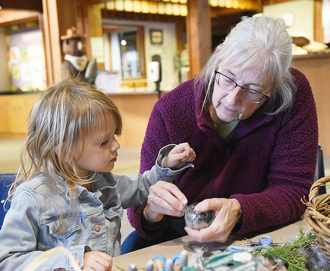 Linda Houston, of Millersburg, assists her granddaughter, Libelle Hedgepeth, 3, in making a Christmas ornament Friday from things found in nature at the Runge Nature Center Shopping Alternatives: Gifts from Nature event.