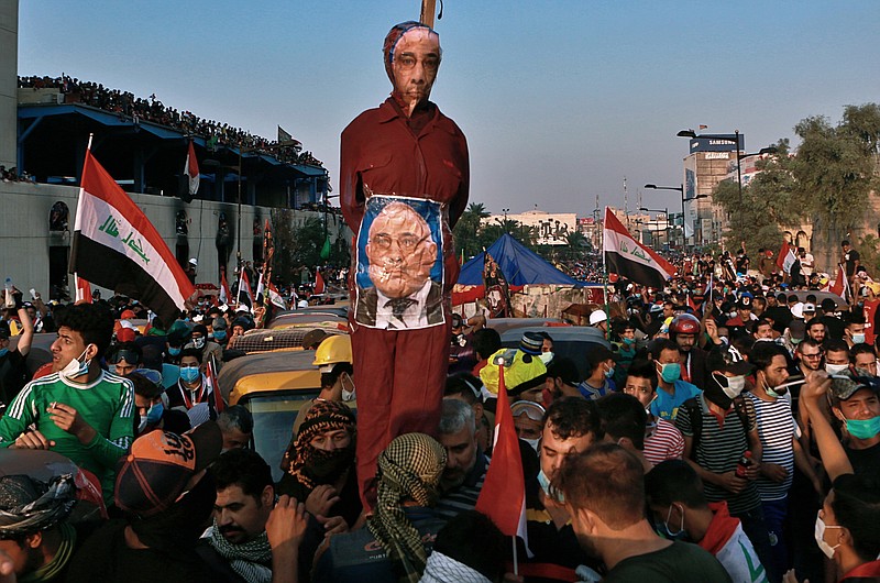 FILE - in this Wednesday, Oct. 30, 2019 file photo, Anti-government protesters hold an effigy of Iraqi Prime Minister Adel Abdel-Mahdi during ongoing protests in Baghdad, Iraq. Celebrations have erupted in Iraq's Tahrir Square, Friday, Nov. 29, where anti-government protesters have been camped out for nearly two months following an announcement by Iraqi Prime Minister Adel Abdul-Mahdi, would be resigning. (AP Photo/Khalid Mohammed, File)