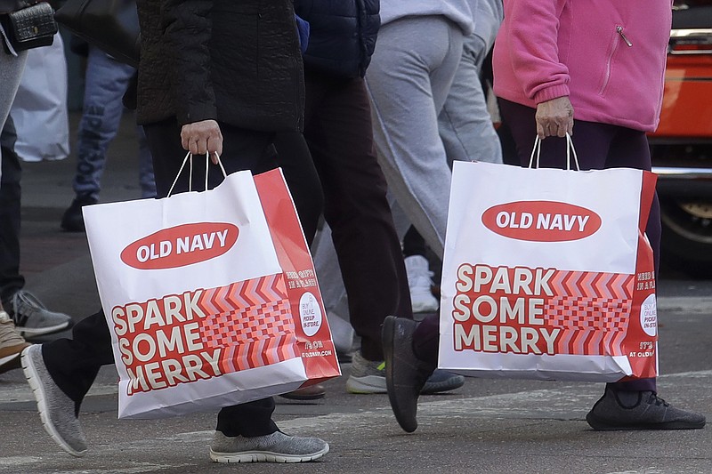 People carry shopping bags while crossing a street in San Francisco, Friday, Nov. 29, 2019. Black Friday once again kicked off the start of the holiday shopping season. (AP Photo/Jeff Chiu)