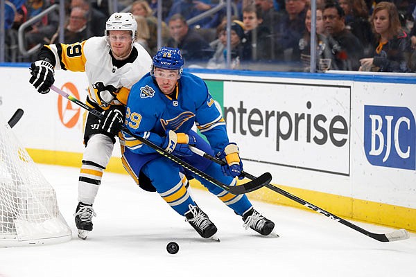 Vince Dunn of the Blues and Jake Guentzel of the Penguins chase after a loose puck during the first period of Saturday night's game in St. Louis.