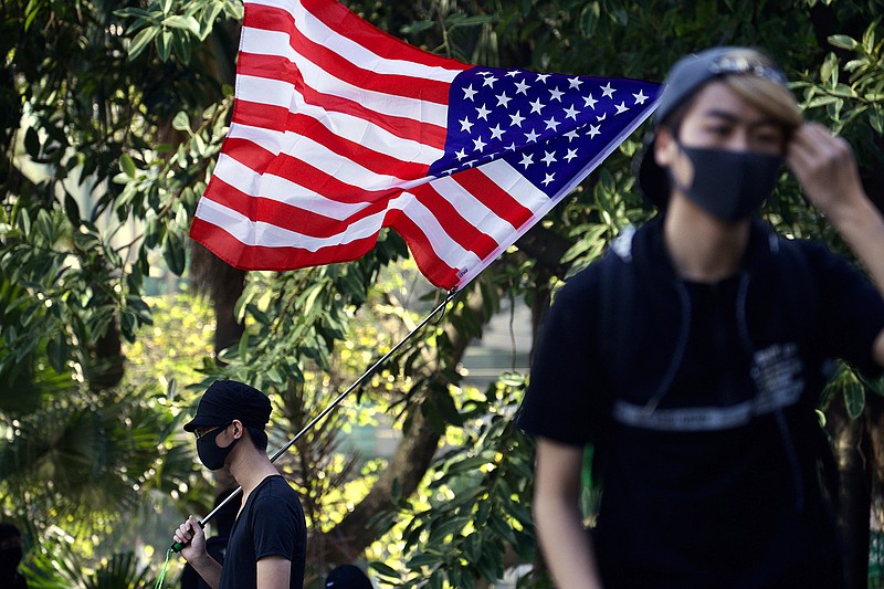 A protester waves an American flag during a rally for students and elderly pro-democracy demonstrators in Hong Kong, Saturday, Nov. 30, 2019. Hundreds of Hong Kong pro-democracy activists rallied Friday outside the British Consulate, urging the city's former colonial ruler to emulate the U.S. and take concrete actions to support their cause, as police ended a blockade of a university campus after 12 days. (AP Photo/Ng Han Guan)