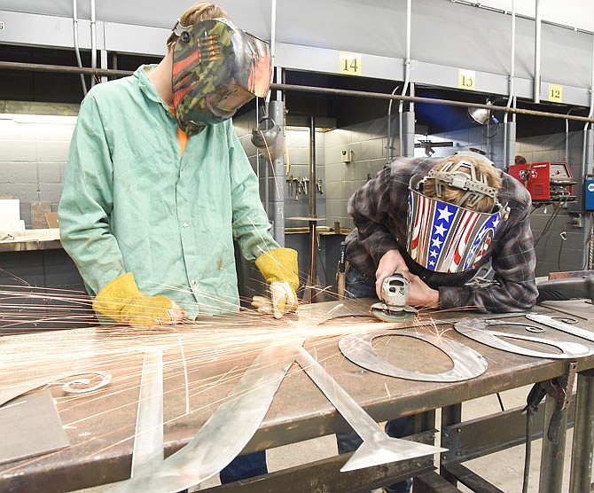 Lane Fennewald, left, looks on as Hunter Kueffer grinds down weld spots on the metal work. Fennewald is a junior at Blair Oaks High School while Kueffer is a Russellville High School junior. They and fellow students in Kenny Thomas' welding class at Nichols Career Center are once again making stainless steel yard ornaments to sell for Christmas.