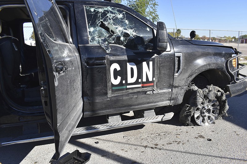 A damaged pick up truck marked with the initials C.D.N., that in Spanish stand for Cartel of the Northeast, stands on the street after a gun battle between Mexican security forces and suspected cartel gunmen, in Villa Union, Mexico, Sunday, Dic. 1, 2019. Mexican security forces on Sunday killed seven more members of a presumed cartel assault force rolled into a town near the Texas border and staged an hour-long attack, officials said, bringing the death toll to at least 21. (AP Photo/Gerardo Sanchez)