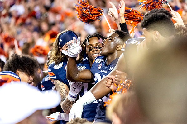 Auburn players sit in the student section as fans rush the field to celebrate an upset of Alabama after Saturday's game in Auburn, Ala.