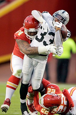 Raiders running back DeAndré Washington is tackled by Chiefs defensive tackle Mike Pennel (64) and safety Juan Thornhill (22) during Sunday's game at Arrowhead Stadium.