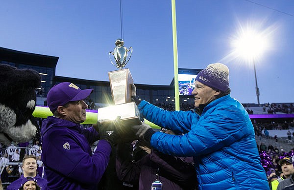 Washington governor Jay Inslee (right) hands Washington coach Chris Petersen the Apple Cup after a win Friday against Washington State in Seattle.