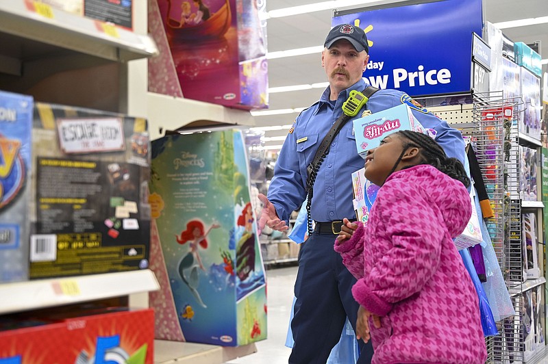 Arkansas firefighter Shane Richardson helps Kaliegh Smith pick out toys during Shop with a Cop and Firefighter on Tuesday, December 3, 2019, at Walmart in Texarkana, Arkansas. On Tuesday, both Texas and Arkansas police officers and firefighters took kids shopping for toys, clothing and Christmas gifts.  