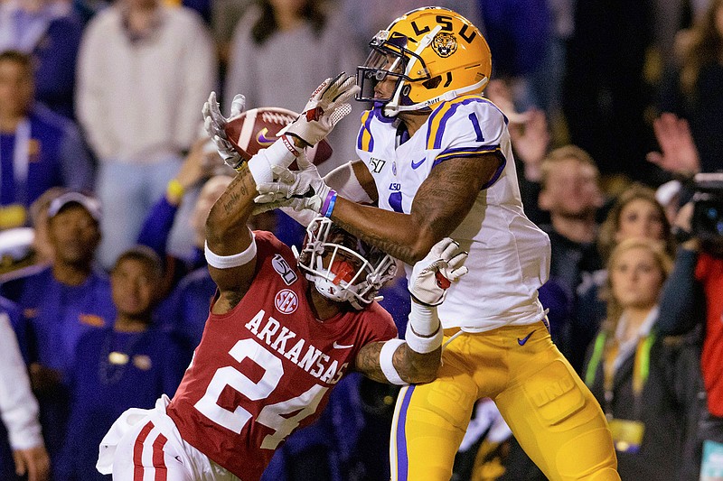  In this Nov. 23, 2019, file photo, LSU wide receiver Ja'Marr Chase (1) catches a pass for a touchdown next to Arkansas defensive back LaDarrius Bishop (24) during the first half of an NCAA college football game, in Baton Rouge, La. No. 1 LSU will meet No. 4 Georgia in the SEC Championship. (AP Photo/Matthew Hinton, File)