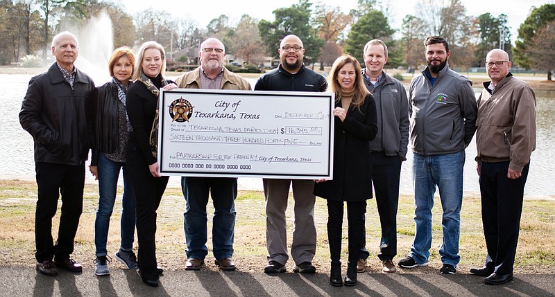 Local nonprofit Partnership for the Pathway presents a check for $16,345 to the city of Texarkana, Texas, on Monday at Spring Lake Park. The donation is to cover matching funds required by a Texas Parks and Wildlife grant the city used to rebuild the walking trail around the park's pond. Pictured, from left, are John Harrison, Julie-Ray Harrison, Lori Davidson, Robby Robertson, Brando Hollis, Michelle Ward, David Orr, Ross Cowling and Mayor Bob Bruggeman. (Submitted photo)
