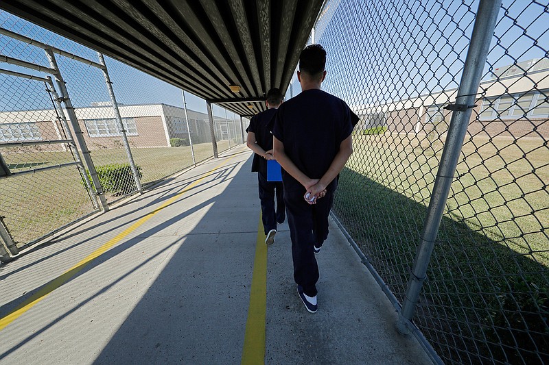  In a Thursday, Sept. 26, 2019 file photo, detainees walk with their hands clasped behind their backs along a line painted on a walkway inside the Winn Correctional Center in Winnfield, La. Asylum seekers detained at an immigration jail in northern Louisiana are refusing to move into their cells in what their families say is a protest of their prolonged detention. U.S. Immigration and Customs Enforcement confirmed Tuesday, Dec. 2 that there is an ongoing protest at the Winn Correctional Center in rural Winnfield. (AP Photo/Gerald Herbert, File)