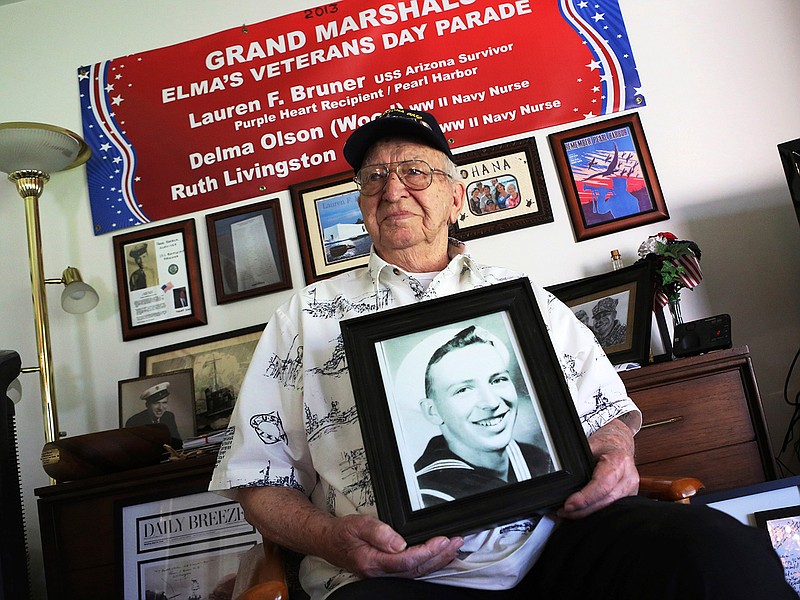 In this Nov. 17, 2016, file photo, Lauren Bruner, a survivor of the USS Arizona which was attacked on Dec. 7, 1941, holds with a 1940 photo of himself at his home in La Mirada, Calif. Divers will place the ashes of Bruner in the wreckage of his ship during a ceremony this weekend in Pearl Harbor, Hawaii.   Bruner died earlier in 2019 at the age of 98. (AP Photo/Reed Saxon, File)