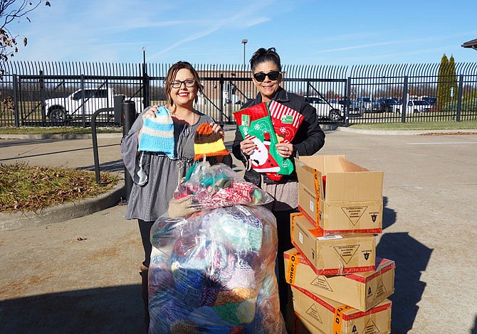 Courtney Harrison, left, executive director of SERVE, and Cara Page, the Fulton Reception and Diagnostic Center's institutional activities coordinator, pose with a giant pile of donations from offenders in the Restorative Justice program. The inmates purchased 200 Christmas stockings for Adopt-a-Family and crocheted 250 hats and scarves. "They said I'd never get these guys crocheting," Page said with a grin.