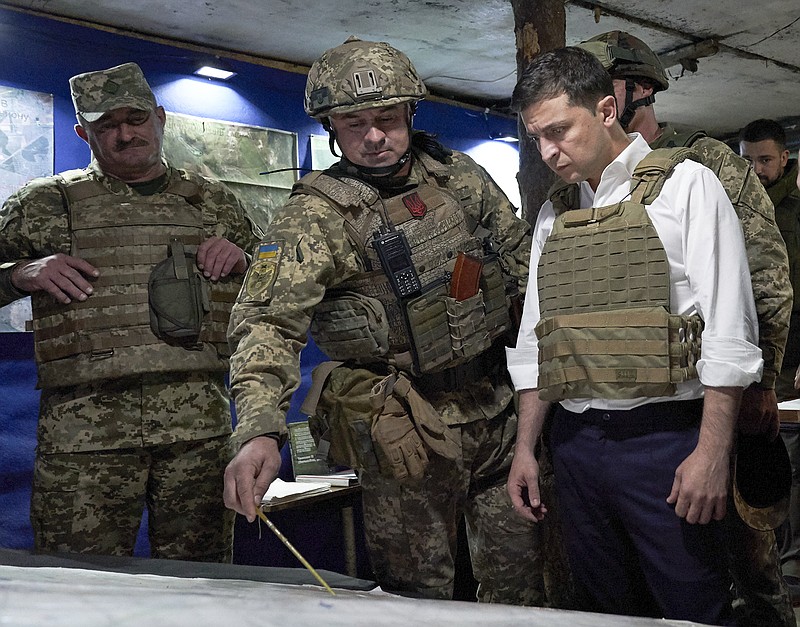 FILE - In this Oct. 14, 2019, file photo, Ukrainian President Volodymyr Zelenskiy, right, listens to a serviceman as he visits the war-hit Donetsk region, eastern Ukraine. For Zelenskiy, a summit meeting with Russia, France and Germany marks a decisive moment in his push to end more than five years of fighting with Moscow-backed separatists in the eastern part of his country. (Ukrainian Presidential Press Office via AP, File)
