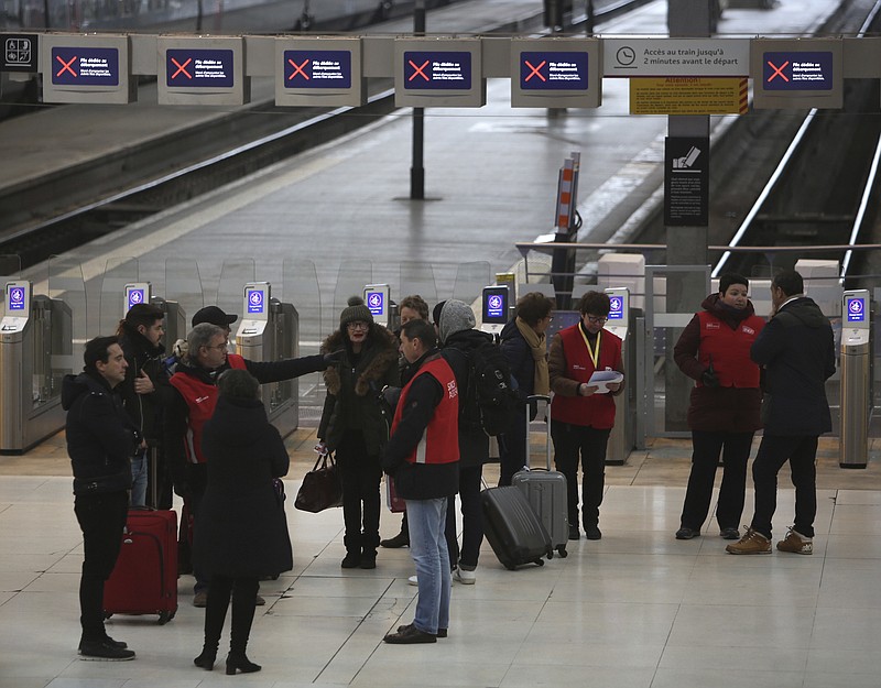 Railway employees, with red jackets, give informations to travellers at the Gare de Lyon train station, Friday, Dec. 6, 2019 in Paris. Frustrated travelers are meeting transportation chaos around France for a second day, as unions dig in for what they hope is a protracted strike against government plans to redesign the national retirement system. (AP Photo/Rafael Yaghobzadeh)