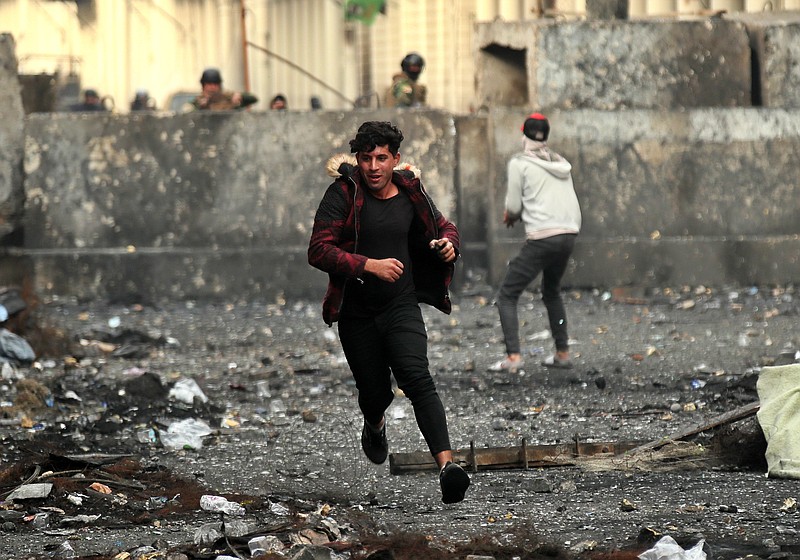 Anti-government protesters throw stones while security forces close Rasheed Street during clashes in Baghdad, Iraq, Friday, Dec. 6, 2019. (AP Photo/Hadi Mizban)