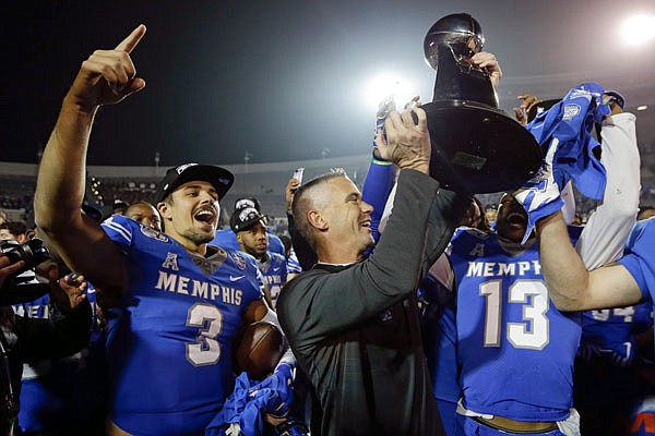 Memphis quarterback Brady White celebrates as coach Mike Norvell lifts the trophy after Saturday's win against Cincinnati in the American Athletic Conference title game in Memphis, Tenn.