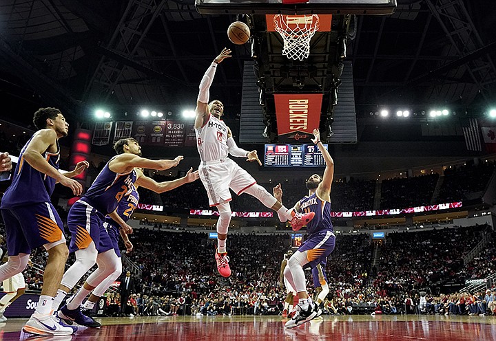 Houston Rockets' Russell Westbrook (0) goes up for a shot as Phoenix Suns' Ricky Rubio (11), Cameron Johnson (23) Dario Saric,, second from left, and Devin Booker (1) defend during the second half of an NBA basketball game Saturday, Dec. 7, 2019, in Houston. The Rockets won 115-109. (AP Photo/David J. Phillip)