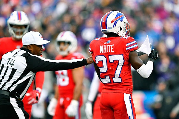 An official attempts to stop Bills cornerback Tre'Davious White from looking at sheets of paper that blew onto the field from the Ravens' bench during Sunday's game in Orchard Park, N.Y