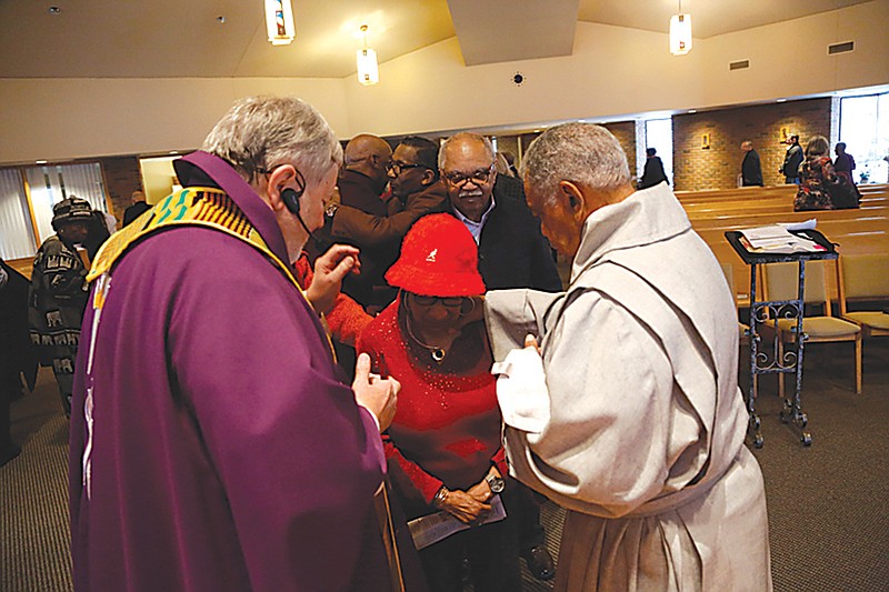 The Rev. Philip Schmitter anoints a parishioner Dec. 1 after Mass at Christ the King Catholic Church in Flint, Mich.