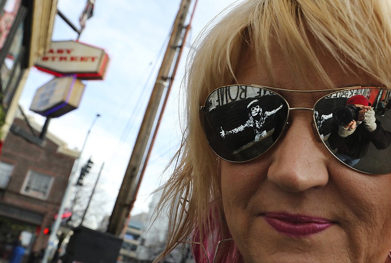 Photographer and book author Karen Mason Blair at Easy Street Records in West Seattle on Friday Dec 6, 2019. The late Andrew Wood of Mother Love Bone is reflected in her glasses, in one of the murals on the outside of the store. (Alan Berner/Seattle Times/TNS)