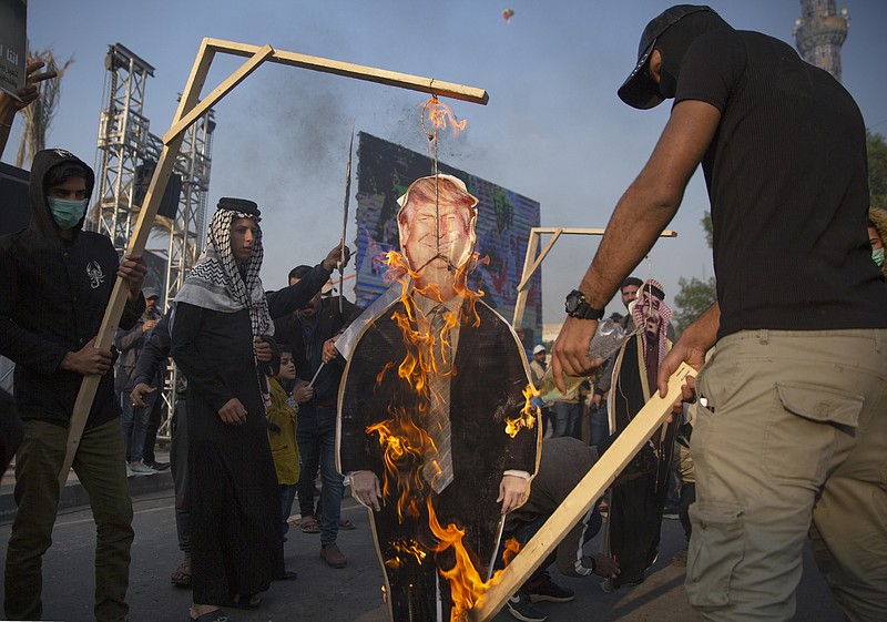 Protesters set on fire a cardboard cutout that depicts US President Donald Trump and hung to a gallows, during a rally for the Shiite group Asaib Ahl al-Haq, in Baghdad, Iraq, Saturday, Dec. 14, 2019.  (AP Photo/Nasser Nasser)