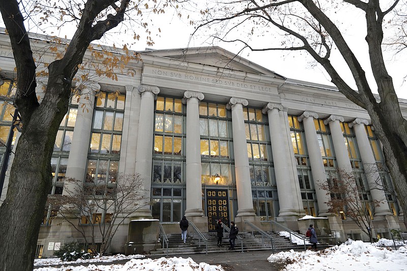 In this Thursday, Dec. 5, 2019 photo passers-by walk near an entrance to a building at Harvard Law School, in Cambridge, Mass. A cluster of commitments to atone for historical ties to slavery marks new territory in a reckoning at U.S. colleges that have responded up until now with monuments, building names changes and public apologies. (AP Photo/Steven Senne)