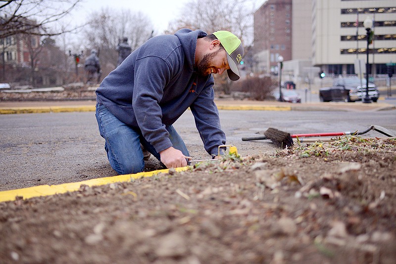 Daryl Glenn, with Rhad Baker Construction, covers a curb with yellow paint Dec. 9 along West Capitol Avenue. The painting is part of the finishing touches for a project that has switched multiple state buildings from a well-water source to a connection with Missouri American Water's system. The move will be a cost saver and improve service and quality.