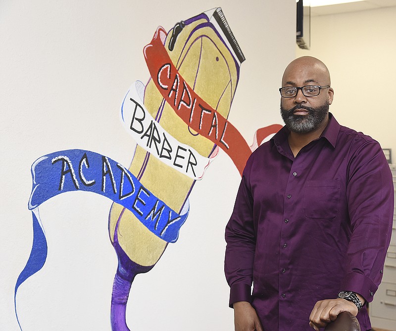 Scott Osby, owner of Capital Barber Academy, poses for a photograph in the lobby of the Ellis Plaza business. 