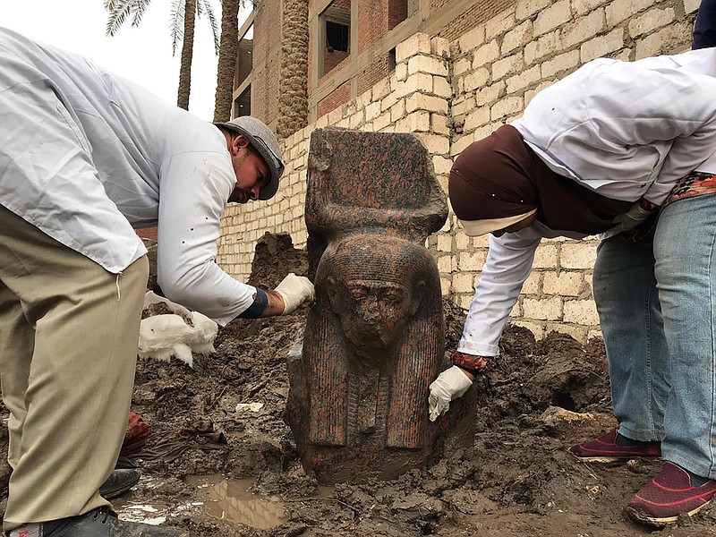 In this Wednesday, Dec. 11, 2019, photo released by Egyptian Ministry of Antiquities, archaeology workers clean a small pink granite statue of Ramses II, near the ancient pyramids of Giza, Egypt. Archeologists in Egypt unveiled two new discoveries, the rare statue of Ramses II, one of the country's most famous pharaohs, and a diminutive ancient sphinx that was found in the southern desert province of Minya. (Egyptian Ministry of Antiquities via AP)