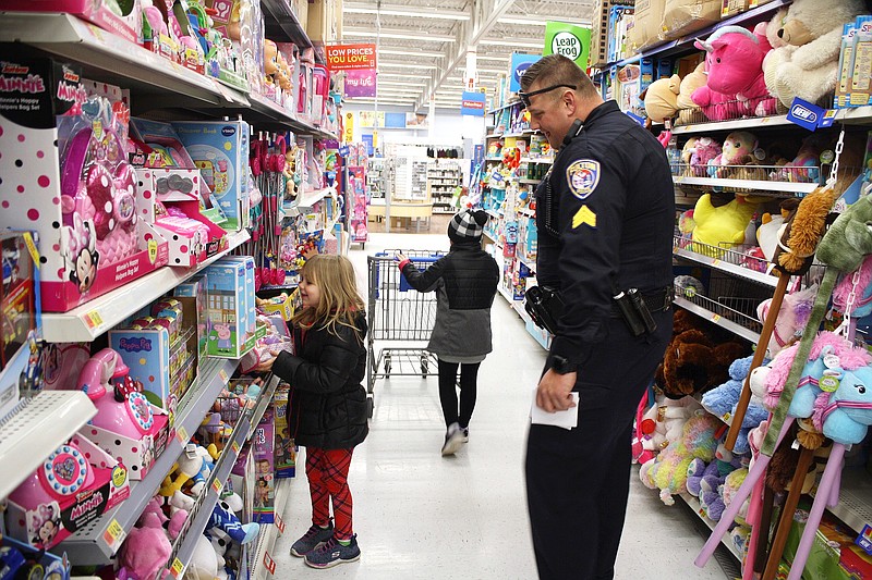 Sgt. Lance Reams accompanies his Shop with a Hero children, Zaferia Smith and Madison Buckholts, through the toy aisle. Forty-three children participated in the event that provides a $100 Christmas shopping trip to Walmart for children in need with a local first responder.