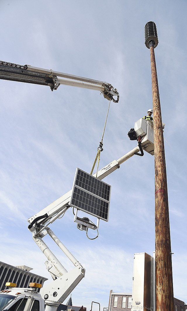 Randy Vandelicht, an electrician with Meyer Electric, prepares to attach the solar panel to the 60-foot pole just installed in the alleyway near the Jefferson City Area Chamber of Commerce. This is one more siren to complement the existing outdoor warning sirens scattered throughout Jefferson City and Cole County. 