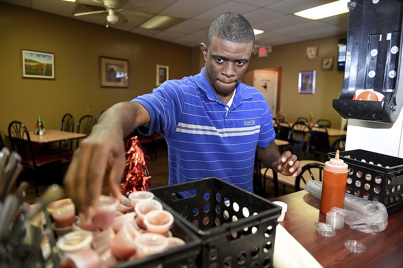 Easter Seals client Barjona Barnes fills sauce containers at Big Mama's Soul Food restaurant in Augusta, Ga., Thursday, Dec. 19, 2019.  (Michael Holahan/The Augusta Chronicle via AP)